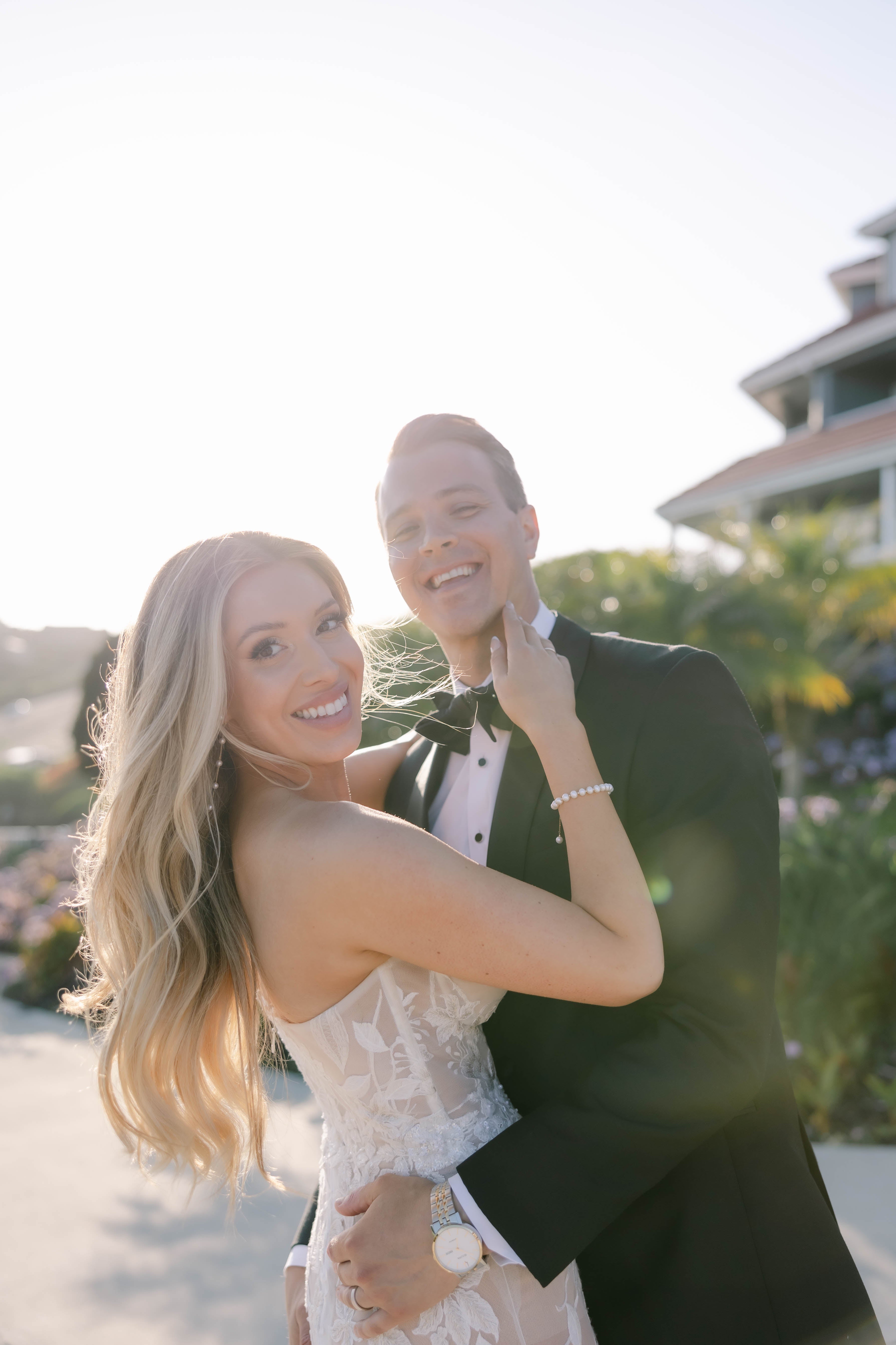 Zac and Nicole embracing outdoors in wedding attire during a sunlit portrait session