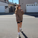 happy woman in brown sweatshirt with Stay Golden on left chest smiling