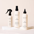Three bottles of Goldie products Miracle mist, Miracle Rinse and Quick Spritz on a light beige background
